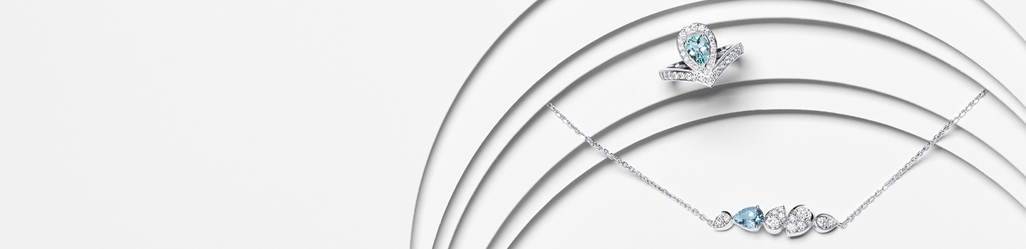 A Chaumet Jos&eacute;phine diamond and aquamarine ring and necklace on a white layered background.